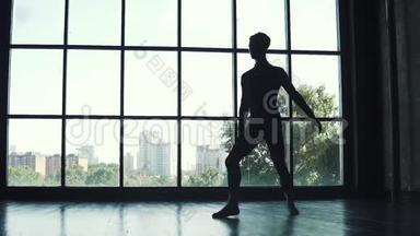 芭蕾舞演员<strong>男</strong>的<strong>剪影</strong>。 年轻人在一扇大窗户的背景下跳经典芭蕾。 慢动作